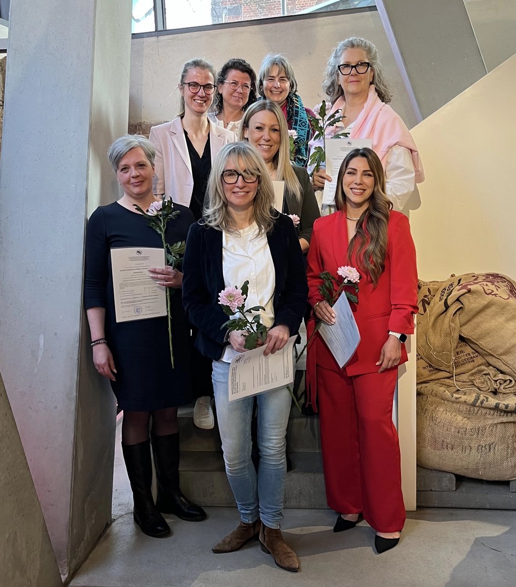 Frauengruppe mit Zertifikaten und Blumen in der Hand