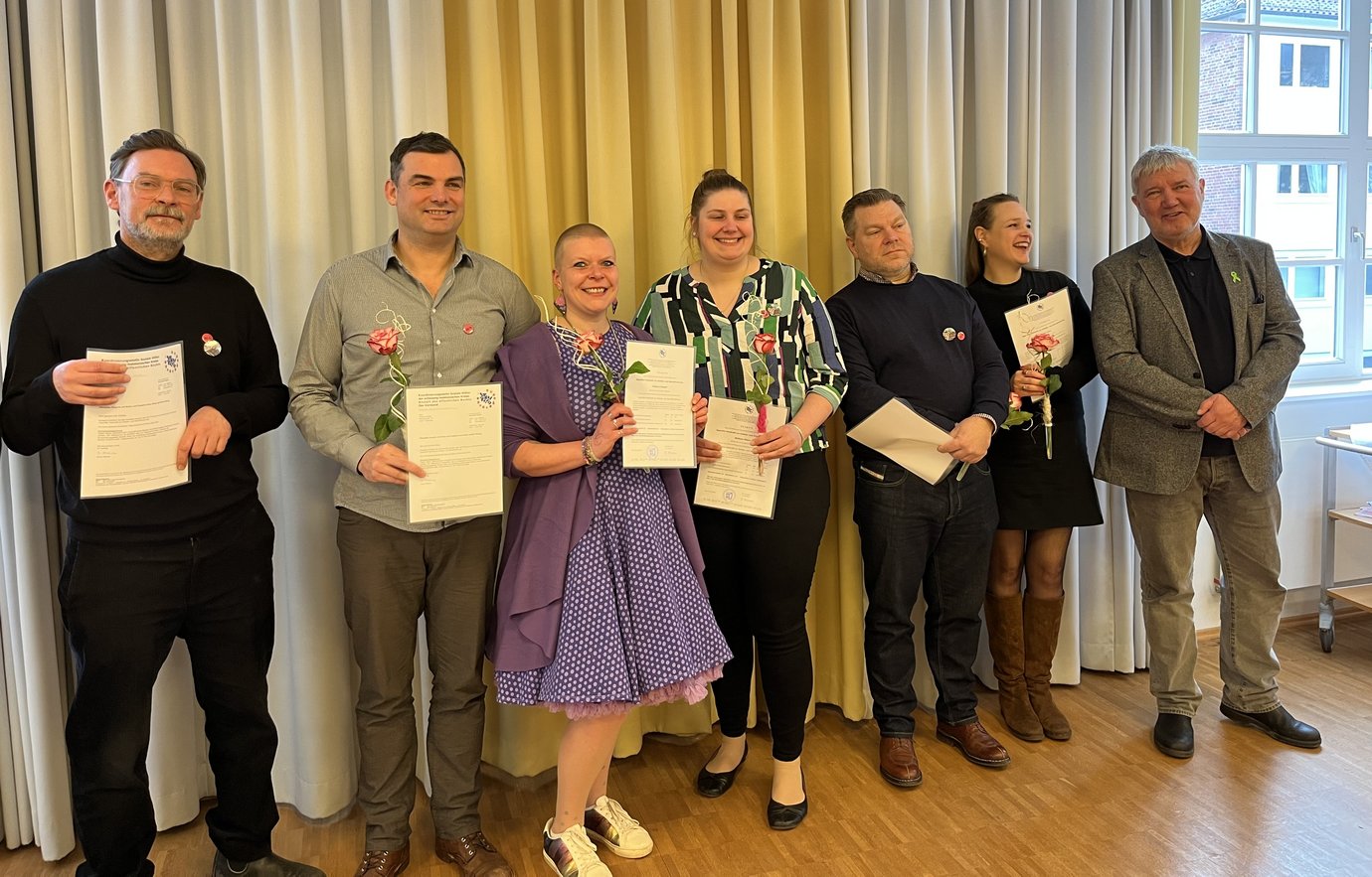 7 Menschen mit Blume in der Hand und Zertifikat