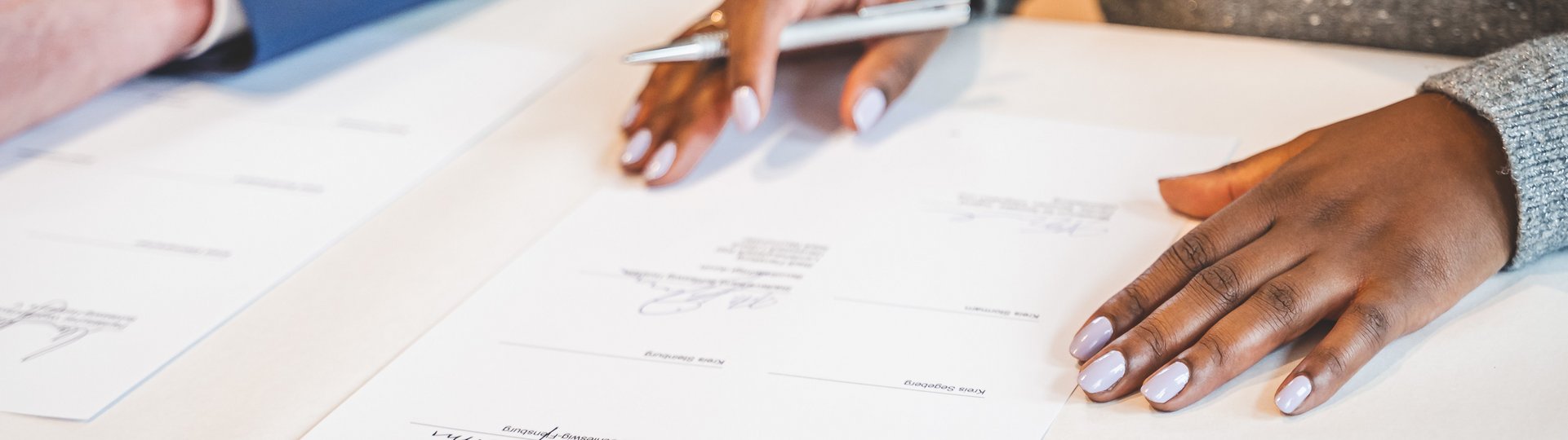Hände, die einen Stift halten, Vertrag als Unterlage